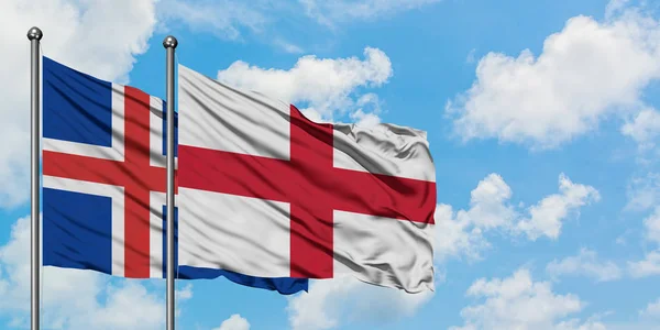 冰岛和英国国旗在风中飘扬，与白云蓝天相一起。外交概念、国际关系. — 图库照片