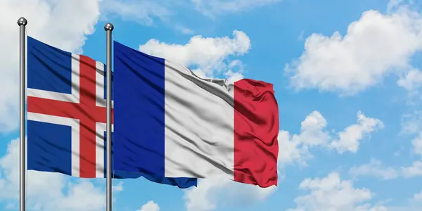 Bandera de Islandia y Francia ondeando en el viento contra el cielo azul nublado blanco juntos. Concepto diplomático, relaciones internacionales . — Foto de Stock
