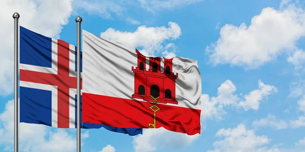 Drapeau de l'Islande et Gibraltar agitant dans le vent contre ciel bleu nuageux blanc ensemble. Concept de diplomatie, relations internationales . — Photo