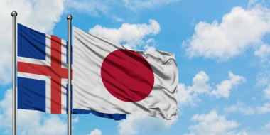 İzlanda ve Japonya bayrağı birlikte beyaz bulutlu mavi gökyüzüne karşı rüzgarda sallayarak. Diplomasi kavramı, uluslararası ilişkiler.