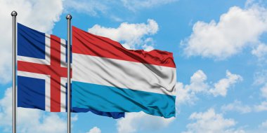 İzlanda ve Lüksemburg bayrağı birlikte beyaz bulutlu mavi gökyüzüne karşı rüzgarda sallayarak. Diplomasi kavramı, uluslararası ilişkiler.