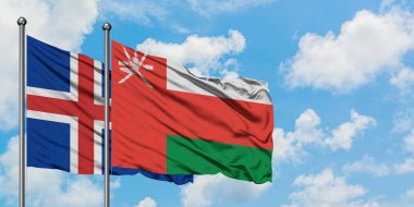 İzlanda ve Umman bayrağı birlikte beyaz bulutlu mavi gökyüzüne karşı rüzgarda sallayarak. Diplomasi kavramı, uluslararası ilişkiler.