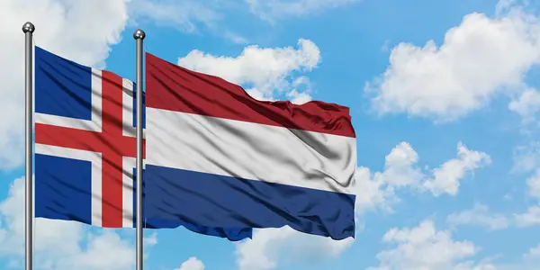 Islanda e Paesi Bassi bandiera sventolando nel vento contro bianco cielo blu nuvoloso insieme. Concetto di diplomazia, relazioni internazionali . — Foto Stock
