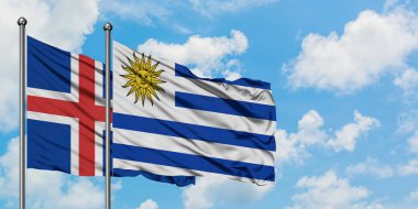 İzlanda ve Uruguay bayrağı birlikte beyaz bulutlu mavi gökyüzüne karşı rüzgarsal sallayarak. Diplomasi kavramı, uluslararası ilişkiler.