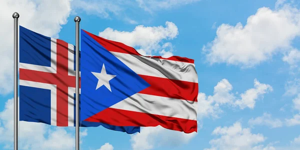 İzlanda ve Porto Riko bayrağı birlikte beyaz bulutlu mavi gökyüzüne karşı rüzgarda sallayarak. Diplomasi kavramı, uluslararası ilişkiler. — Stok fotoğraf