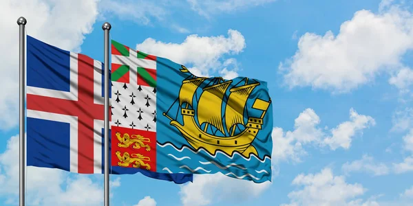 Island och Saint Pierre och Miquelon flagga vifta i vinden mot vit grumlig blå himmel tillsammans. Diplomatisk koncept, internationella relationer. — Stockfoto
