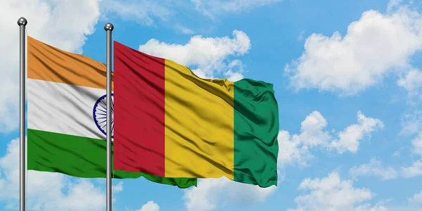 Bandera de India y Guinea ondeando en el viento contra el cielo azul nublado blanco juntos. Concepto diplomático, relaciones internacionales . — Foto de Stock