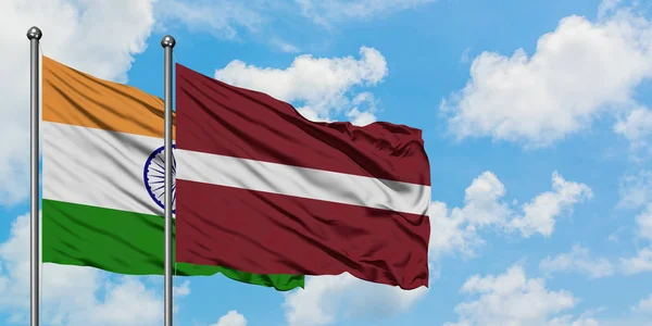 Bandera de la India y Letonia ondeando en el viento contra el cielo azul nublado blanco juntos. Concepto diplomático, relaciones internacionales . — Foto de Stock