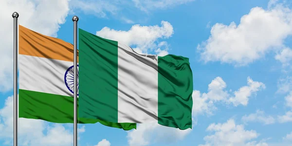 一緒に白い曇り青い空に対して風に手を振るインドとナイジェリアの旗。外交概念、国際関係. — ストック写真