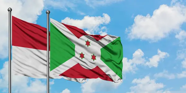 Bandera de Irak y Burundi ondeando en el viento contra el cielo azul nublado blanco juntos. Concepto diplomático, relaciones internacionales . — Foto de Stock