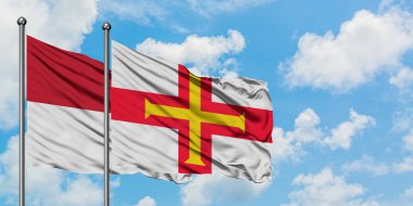 Irak ve Guernsey bayrağı birlikte beyaz bulutlu mavi gökyüzüne karşı rüzgarda sallayarak. Diplomasi kavramı, uluslararası ilişkiler.