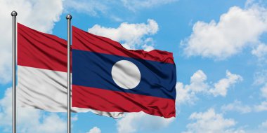 Irak ve Laos bayrağı birlikte beyaz bulutlu mavi gökyüzüne karşı rüzgarda sallayarak. Diplomasi kavramı, uluslararası ilişkiler.