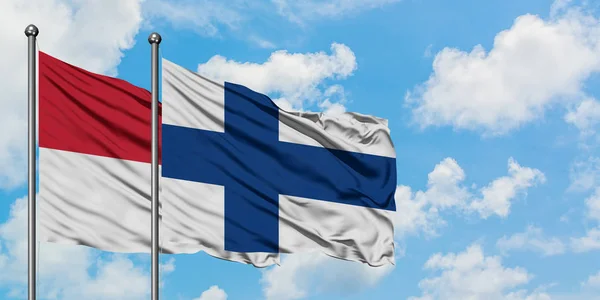 Iraq e Finlandia sventolano bandiera nel vento contro bianco cielo blu nuvoloso insieme. Concetto di diplomazia, relazioni internazionali . — Foto Stock