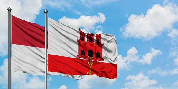 Iraque e Gibraltar acenando com o vento contra o céu azul nublado branco juntos. Conceito de diplomacia, relações internacionais . — Fotografia de Stock