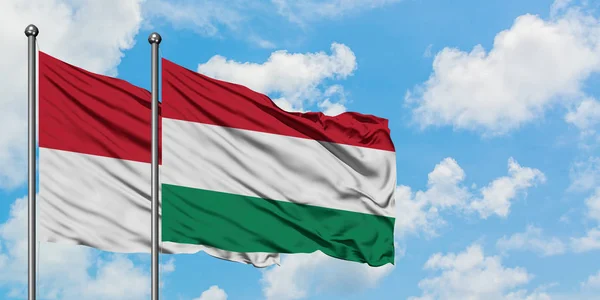 Bandera de Irak y Hungría ondeando en el viento contra el cielo azul nublado blanco juntos. Concepto diplomático, relaciones internacionales . — Foto de Stock