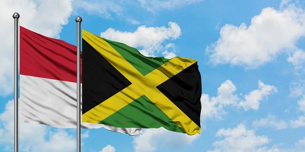 Bandera de Irak y Jamaica ondeando en el viento contra el cielo azul nublado blanco juntos. Concepto diplomático, relaciones internacionales . — Foto de Stock