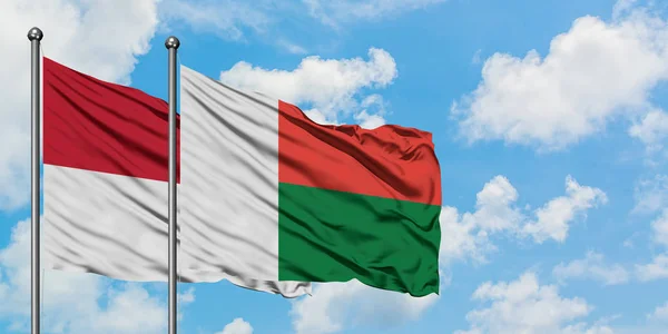 Drapeau de l'Irak et de Madagascar agitant dans le vent contre ciel bleu nuageux blanc ensemble. Concept de diplomatie, relations internationales . — Photo