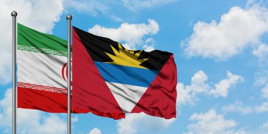 İran ve Antigua ve Barbuda bayrağı birlikte beyaz bulutlu mavi gökyüzüne karşı rüzgarda sallayarak. Diplomasi kavramı, uluslararası ilişkiler.