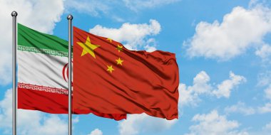 İran ve Çin bayrağı birlikte beyaz bulutlu gökyüzüne karşı rüzgarda dalgalanıyor. Diplomasi kavramı, uluslararası ilişkiler.