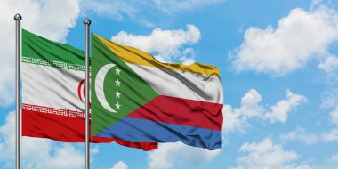 İran ve Komorbayrağı birlikte beyaz bulutlu mavi gökyüzüne karşı rüzgarsal sallayarak. Diplomasi kavramı, uluslararası ilişkiler.