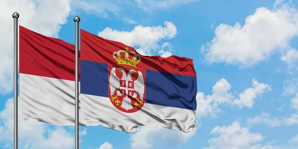 Bandera de Irak y Serbia ondeando en el viento contra el cielo azul nublado blanco juntos. Concepto diplomático, relaciones internacionales . — Foto de Stock