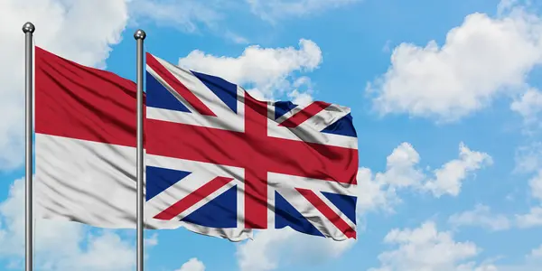 Irak och Storbritannien flagga vifta i vinden mot vit grumlig blå himmel tillsammans. Diplomatisk koncept, internationella relationer. — Stockfoto