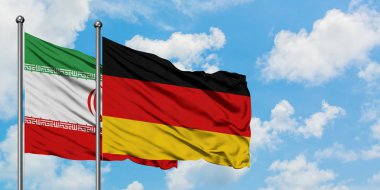 İran ve Almanya bayrağı birlikte beyaz bulutlu mavi gökyüzüne karşı rüzgarsal sallayarak. Diplomasi kavramı, uluslararası ilişkiler.