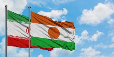 İran ve Nijer bayrağı birlikte beyaz bulutlu mavi gökyüzüne karşı rüzgarda sallayarak. Diplomasi kavramı, uluslararası ilişkiler.