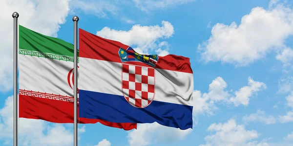 Bandera de Irán y Croacia ondeando en el viento contra el cielo azul nublado blanco juntos. Concepto diplomático, relaciones internacionales . — Foto de Stock