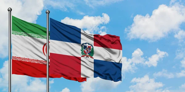 Irã e República Dominicana acenando com o vento contra o céu azul nublado branco juntos. Conceito de diplomacia, relações internacionais . — Fotografia de Stock