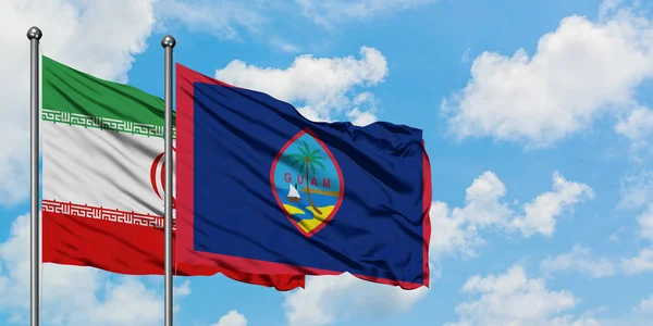 Bandera de Irán y Guam ondeando en el viento contra el cielo azul nublado blanco juntos. Concepto diplomático, relaciones internacionales . — Foto de Stock