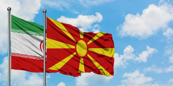 Bandera de Irán y Macedonia ondeando en el viento contra el cielo azul nublado blanco juntos. Concepto diplomático, relaciones internacionales . — Foto de Stock