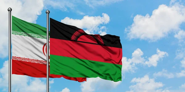 Bandera de Irán y Malawi ondeando en el viento contra el cielo azul nublado blanco juntos. Concepto diplomático, relaciones internacionales . — Foto de Stock