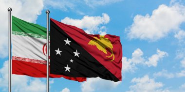 İran ve Papua Yeni Gine bayrağı birlikte beyaz bulutlu mavi gökyüzüne karşı rüzgarsal sallayarak. Diplomasi kavramı, uluslararası ilişkiler.