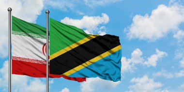 İran ve Tanzanya bayrağı birlikte beyaz bulutlu mavi gökyüzüne karşı rüzgarsal sallayarak. Diplomasi kavramı, uluslararası ilişkiler.