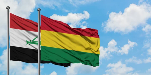 Bandera de Irak y Bolivia ondeando en el viento contra el cielo azul nublado blanco juntos. Concepto diplomático, relaciones internacionales . — Foto de Stock