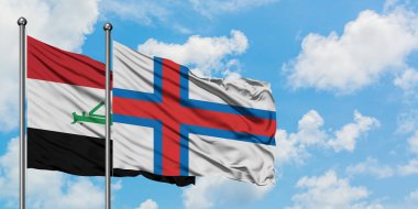 Irak ve Faroe Adaları bayrağı birlikte beyaz bulutlu mavi gökyüzüne karşı rüzgarda sallayarak. Diplomasi kavramı, uluslararası ilişkiler.
