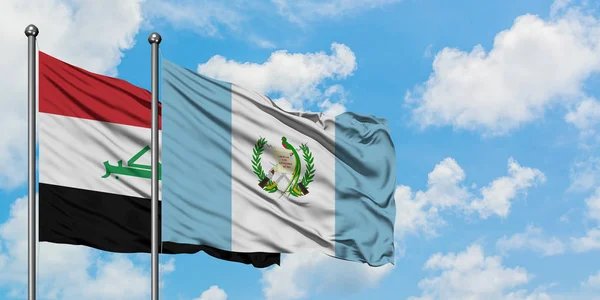 Bandera de Irak y Guatemala ondeando en el viento contra el cielo azul nublado blanco juntos. Concepto diplomático, relaciones internacionales . — Foto de Stock