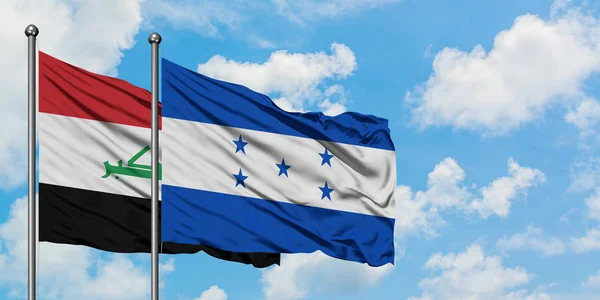 Bandera de Irak y Honduras ondeando en el viento contra el cielo azul nublado blanco juntos. Concepto diplomático, relaciones internacionales . — Foto de Stock
