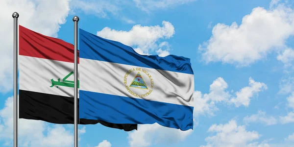 Bandera de Irak y Nicaragua ondeando en el viento contra el cielo azul nublado blanco juntos. Concepto diplomático, relaciones internacionales . — Foto de Stock