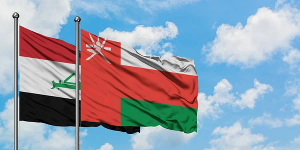 Bandera de Irak y Omán ondeando en el viento contra el cielo azul nublado blanco juntos. Concepto diplomático, relaciones internacionales . — Foto de Stock