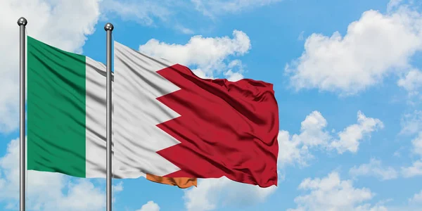 Bandera de Irlanda y Bahréin ondeando en el viento contra el cielo azul nublado blanco juntos. Concepto diplomático, relaciones internacionales . — Foto de Stock
