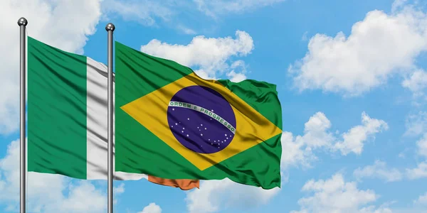 Bandera de Irlanda y Brasil ondeando en el viento contra el cielo azul nublado blanco juntos. Concepto diplomático, relaciones internacionales . — Foto de Stock