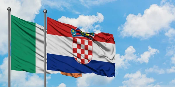Bandera de Irlanda y Croacia ondeando en el viento contra el cielo azul nublado blanco juntos. Concepto diplomático, relaciones internacionales . — Foto de Stock