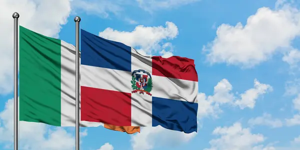 Bandera de Irlanda y República Dominicana ondeando en el viento contra el cielo azul nublado blanco juntos. Concepto diplomático, relaciones internacionales . — Foto de Stock