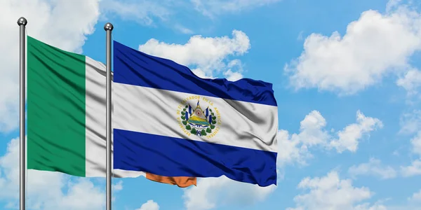 Bandera de Irlanda y El Salvador ondeando en el viento contra el cielo azul nublado blanco juntos. Concepto diplomático, relaciones internacionales . — Foto de Stock