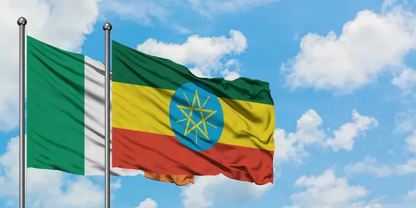 一緒に白い曇り青い空に対して風に振るアイルランドとエチオピアの旗。外交概念、国際関係. — ストック写真