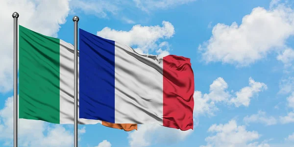 Bandera de Irlanda y Francia ondeando en el viento contra el cielo azul nublado blanco juntos. Concepto diplomático, relaciones internacionales . — Foto de Stock