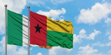 İrlanda ve Gine Bissau bayrağı birlikte beyaz bulutlu mavi gökyüzüne karşı rüzgarda sallayarak. Diplomasi kavramı, uluslararası ilişkiler.