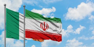 İrlanda ve İran bayrağı birlikte beyaz bulutlu mavi gökyüzüne karşı rüzgarda sallayarak. Diplomasi kavramı, uluslararası ilişkiler.